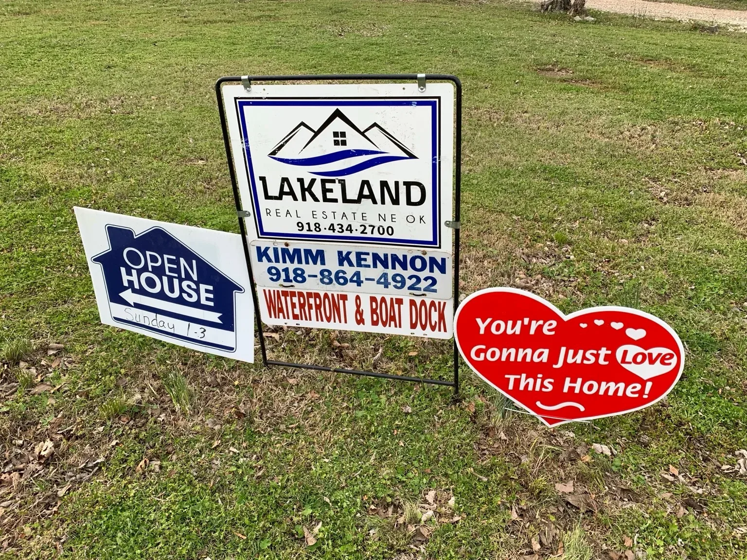 Real estate signs for Kimm Kennon and an open house on a green lawn in Pryor