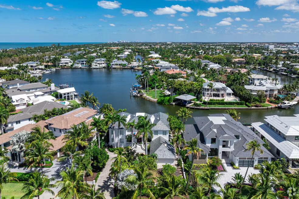 Drone aerial of Aqualane Shores waterfront homes with canals, pools, and tropical landscaping