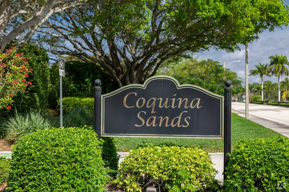 Coquina Sands community entrance sign with gold lettering on a black metal sign in a landscaped setting