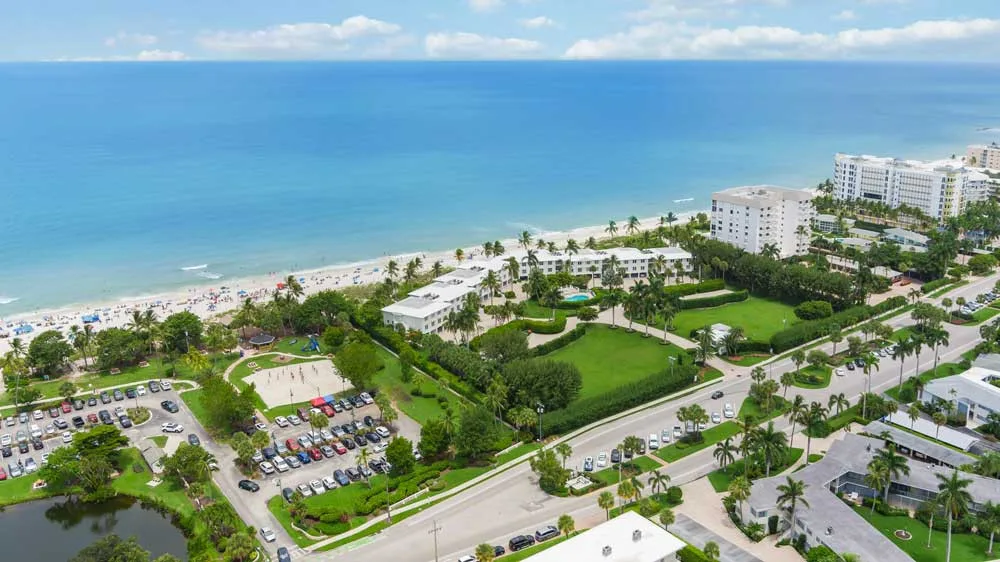 Wide aerial view of Coquina Sands beachfront with white condominiums and turquoise Gulf waters