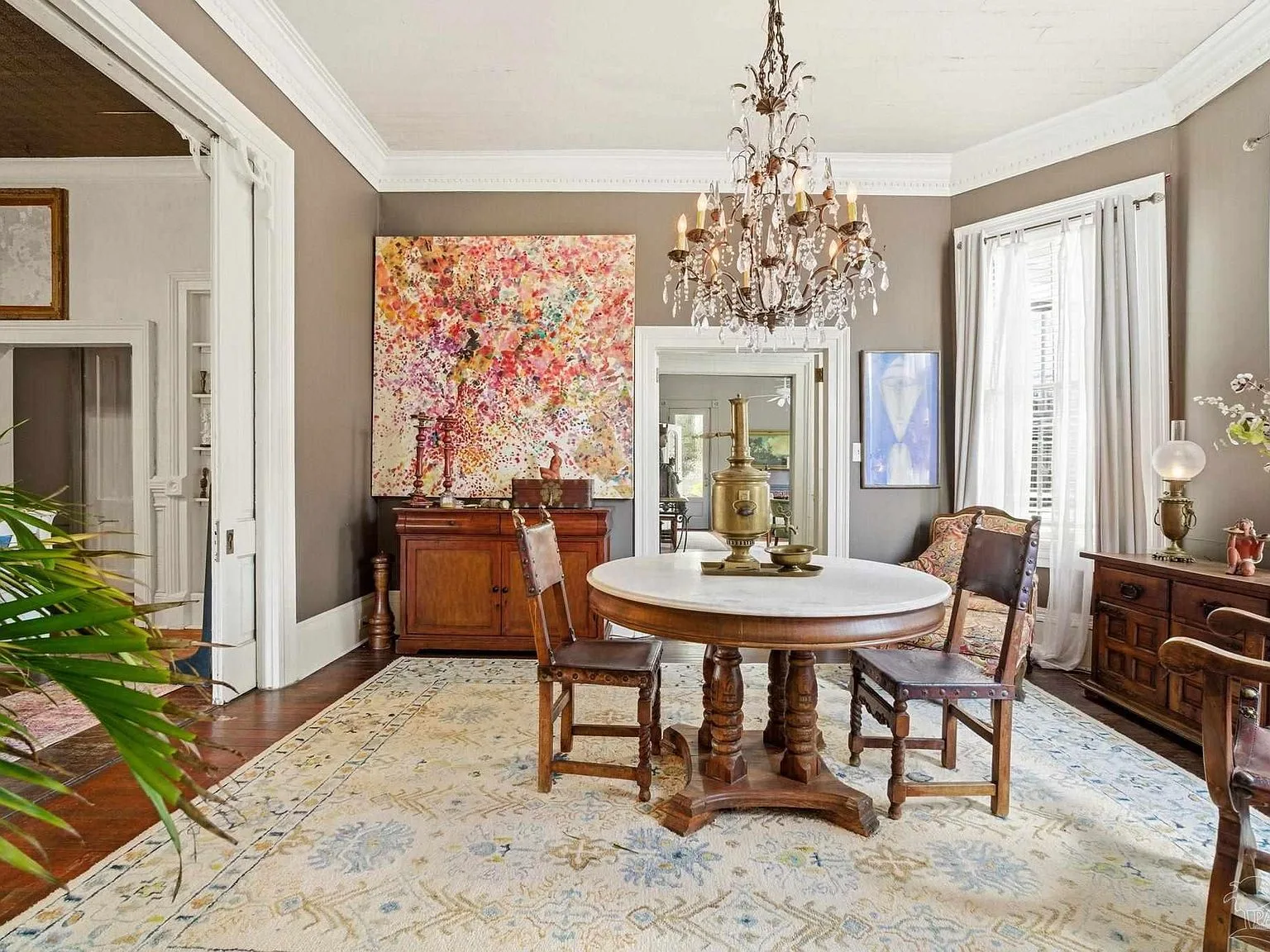 The formal dining room with high ceilings, intricate crown molding, and a crystal chandelier.