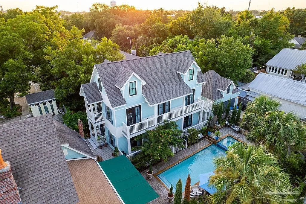 Golden hour aerial view of the main house and carriage house wrapped around the swimming pool and lounge terrace.
