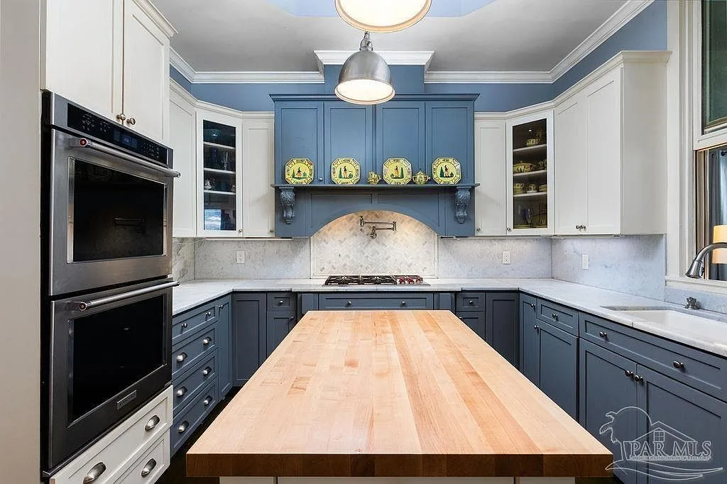 Navy and white cabinetry, marble counters, and a wood-topped island in the estate kitchen.