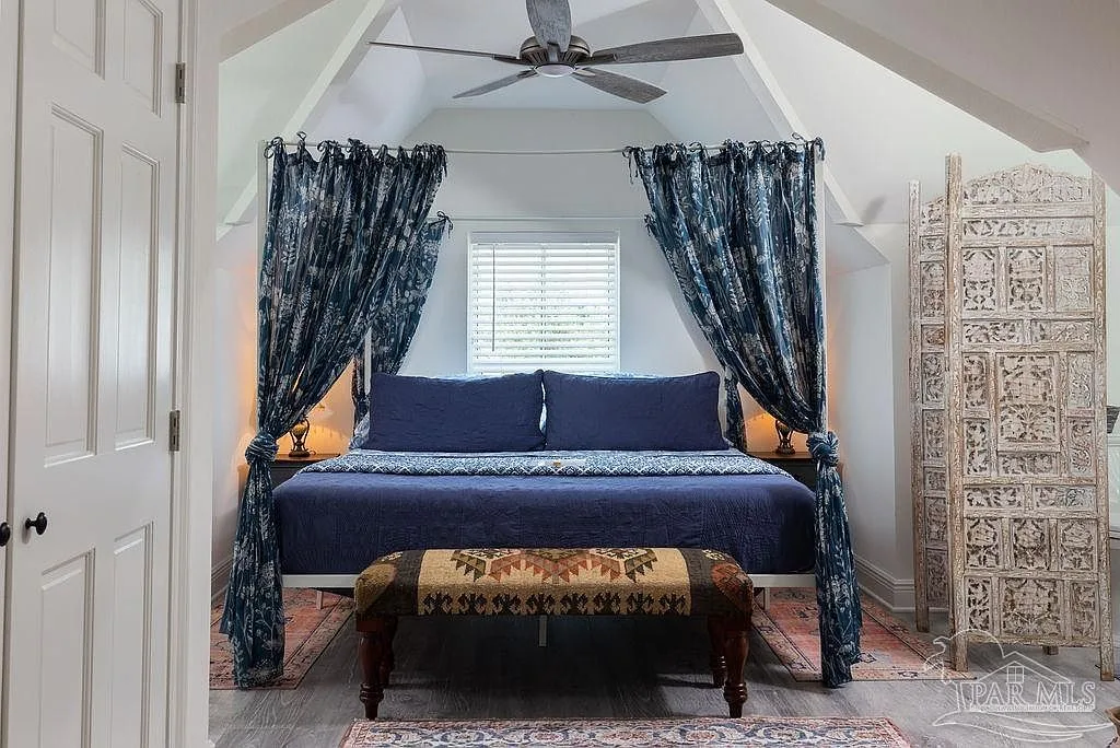 An attic loft suite with a sloping ceiling, canopy bed, and soft, bright styling.