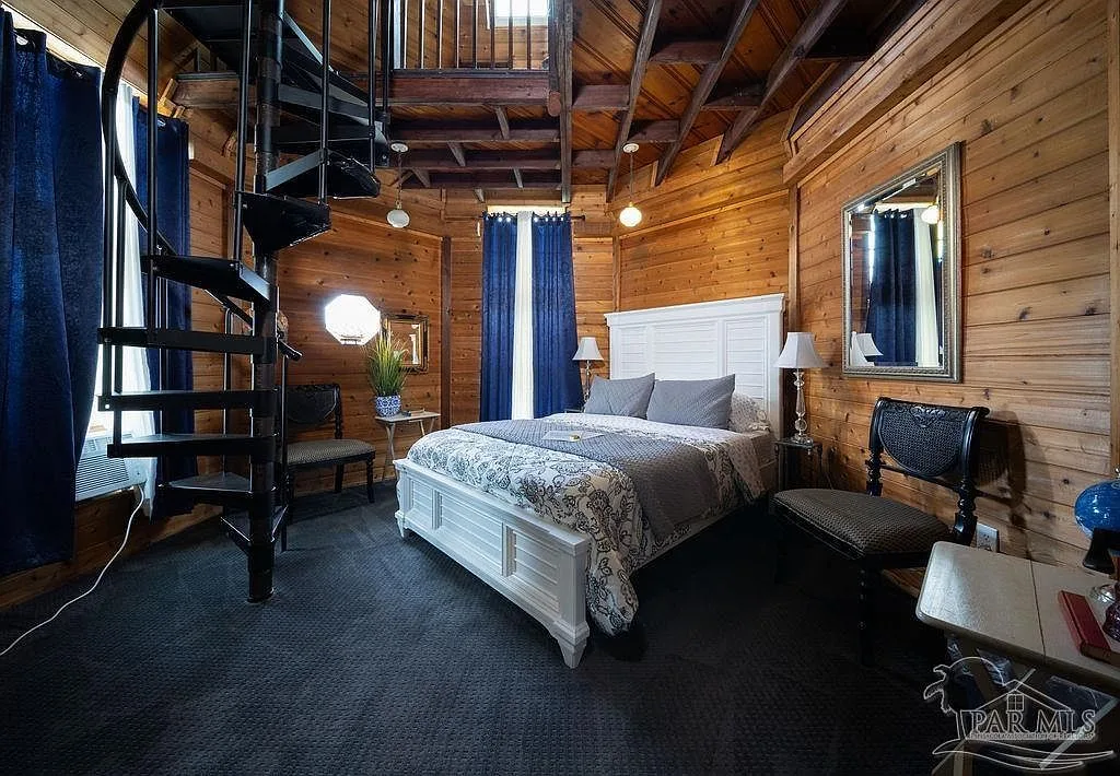 The turret suite bedroom with warm wood paneling and windows wrapping the octagonal tower.
