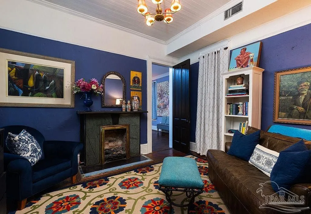 A bold blue-walled sitting room with a fireplace and chandelier, one of several drawing rooms in the estate.