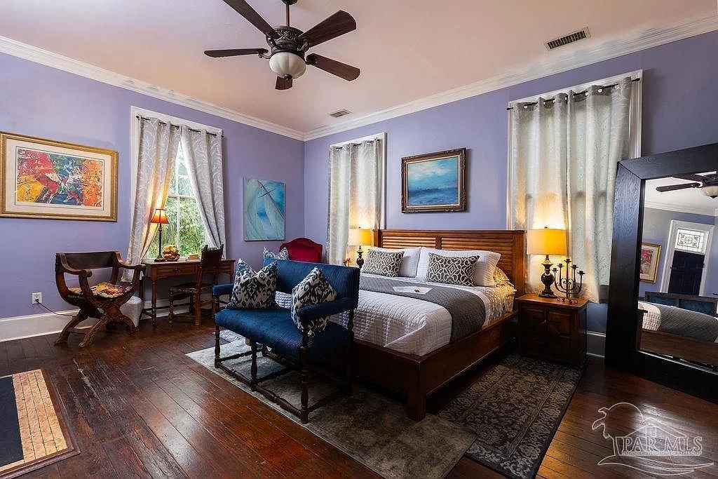 A master suite with lavender walls, hardwood floors, and soft, romantic light.