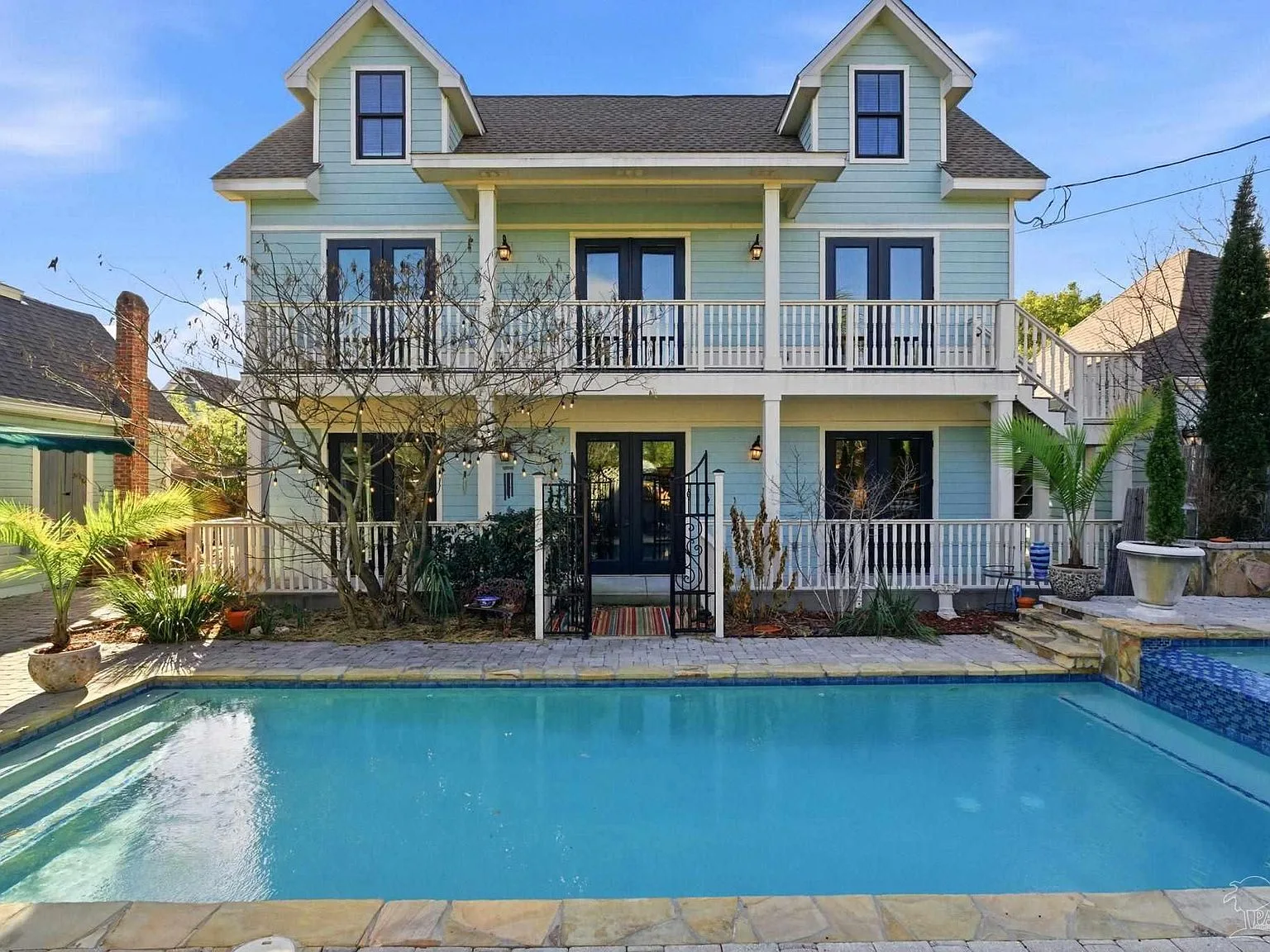 The rear Queen Anne facade with covered patios above the sunlit pool.