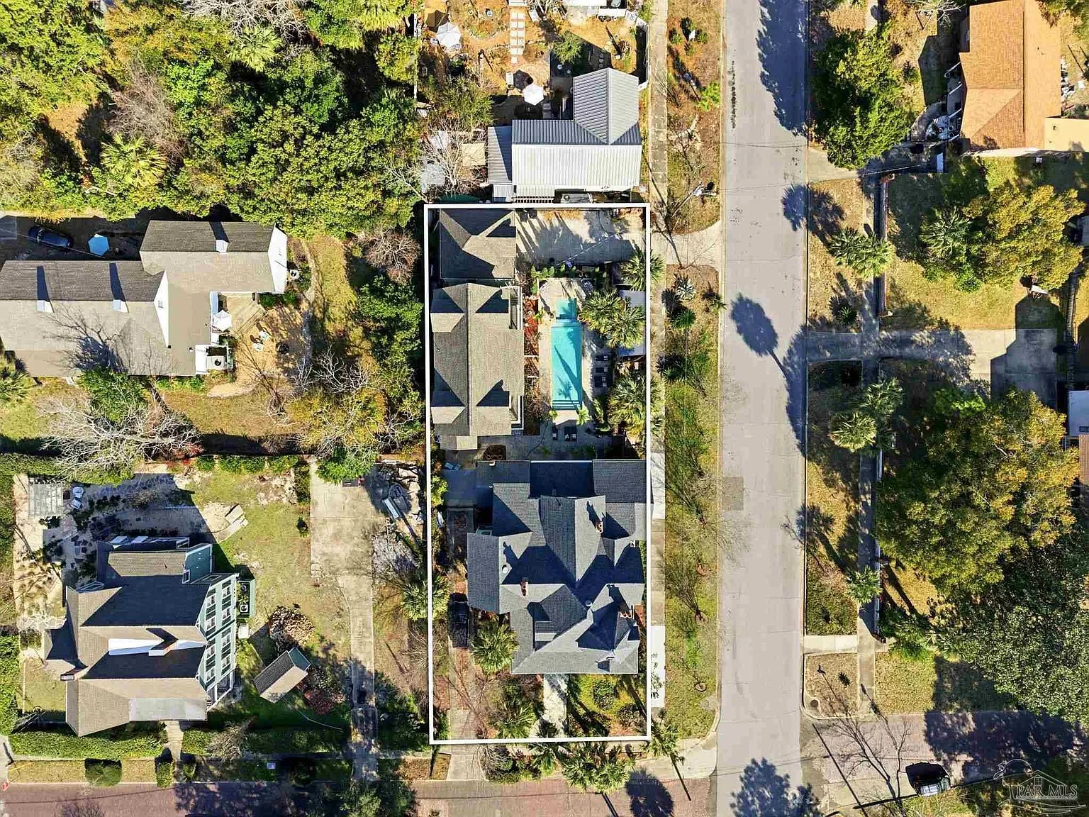 Direct overhead aerial of the three-story main house and detached carriage house with the central heated saltwater pool.