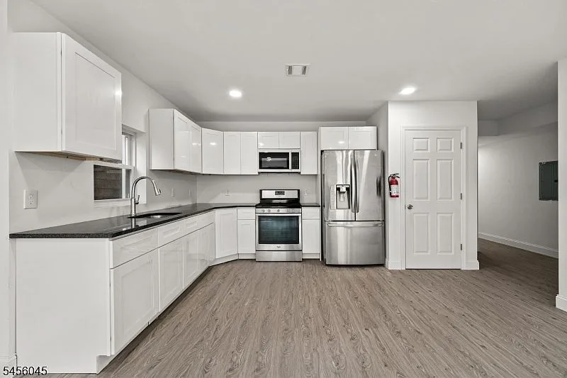 Renovated kitchen with white cabinetry, stainless steel stove and refrigerator, recessed lighting, and wood-look flooring at 113 Marshall St.
