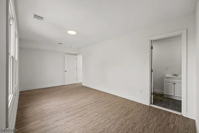 Primary bedroom with natural side light and an attached private bathroom with a white vanity.