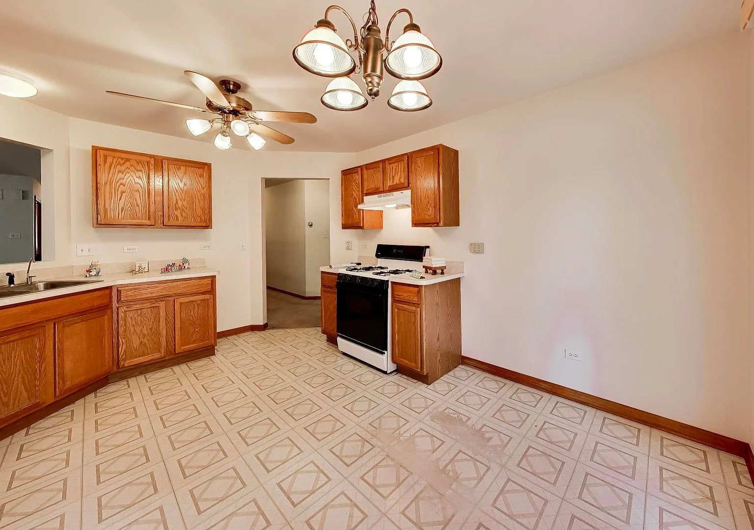 Kitchen with oak cabinetry, white counters, and geometric tile floor