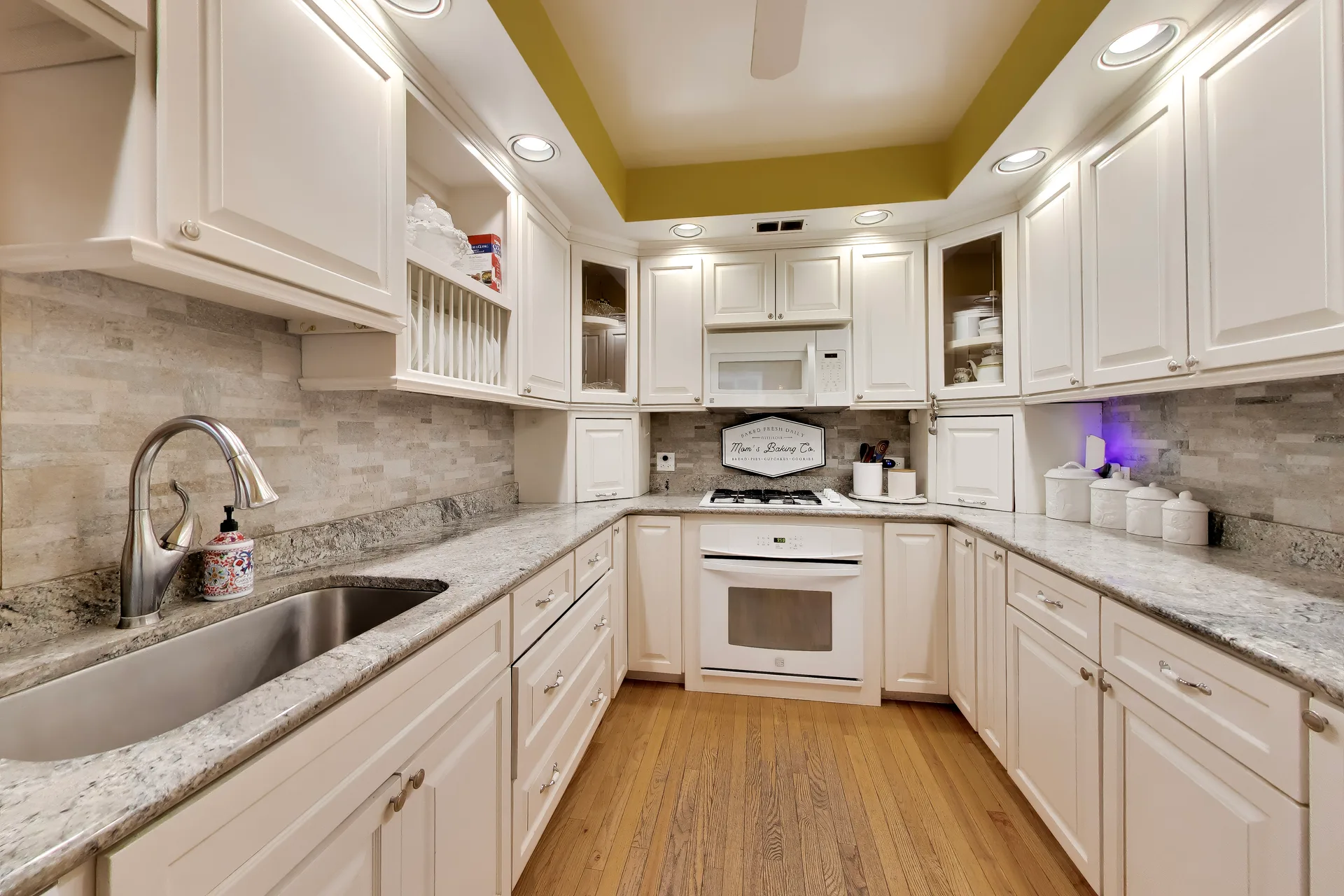 Galley kitchen with stone backsplash and hardwood floors