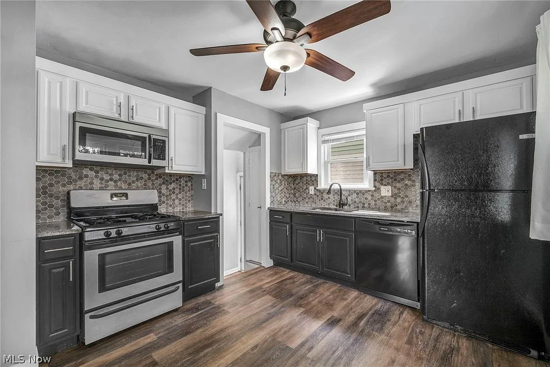 Wide view of the updated kitchen with two-tone cabinets and wood-look flooring