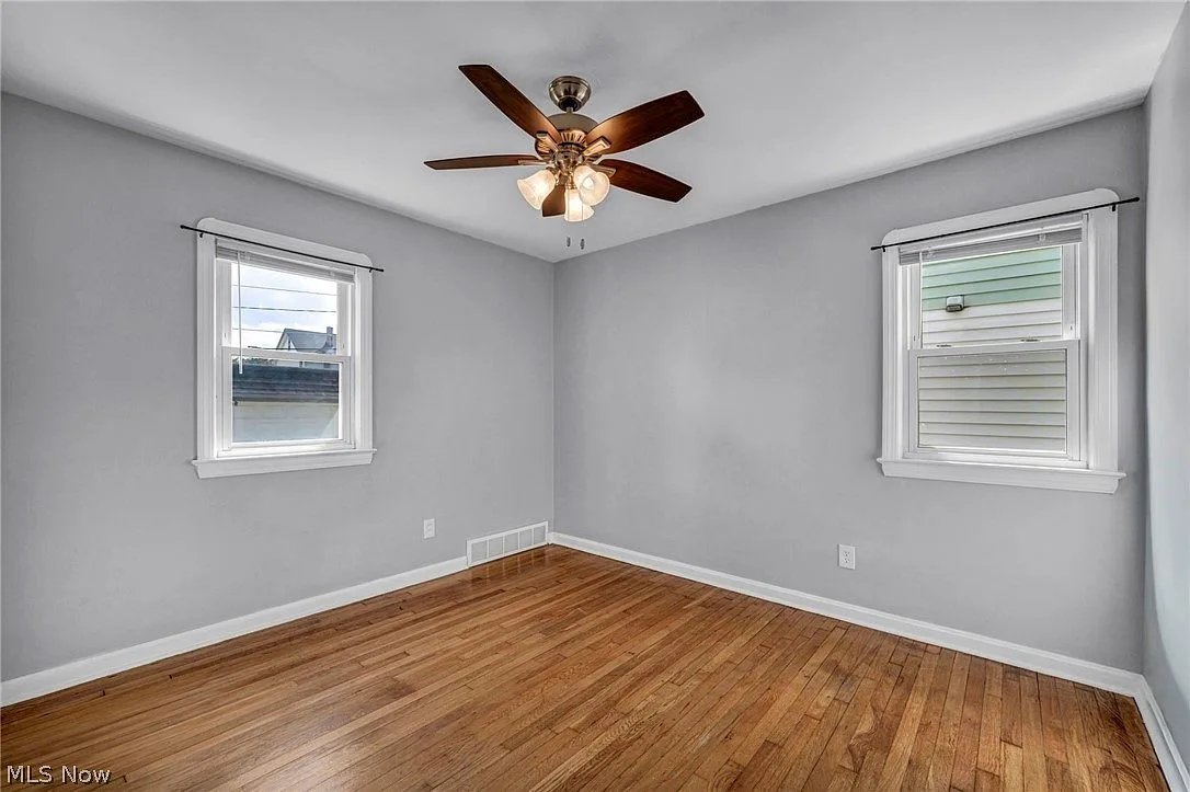 Bedroom with hardwood floors, light gray walls, and white baseboard trim