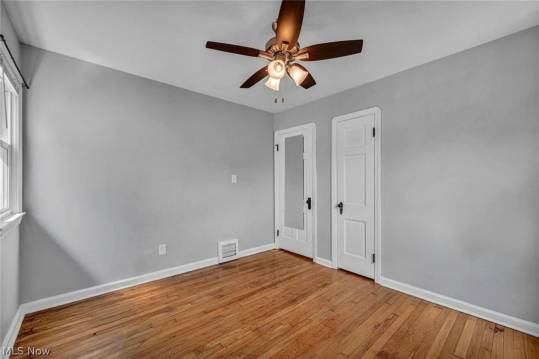 Secondary bedroom with hardwood floors, neutral walls, and white trim