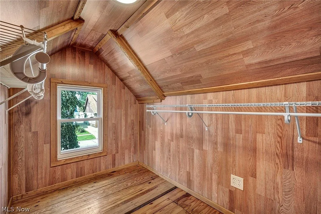 Wood-paneled bonus room upstairs with sloped ceiling and daylight