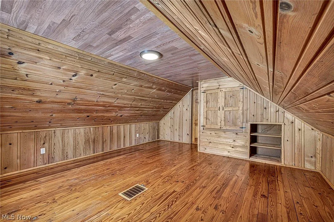 Upstairs primary bedroom with knotty pine paneling and sloped ceilings