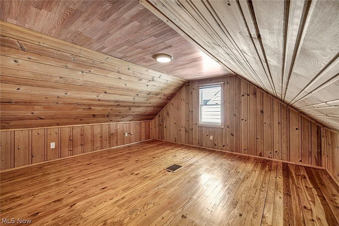 Upstairs primary bedroom with vaulted wood ceiling and hardwood floor