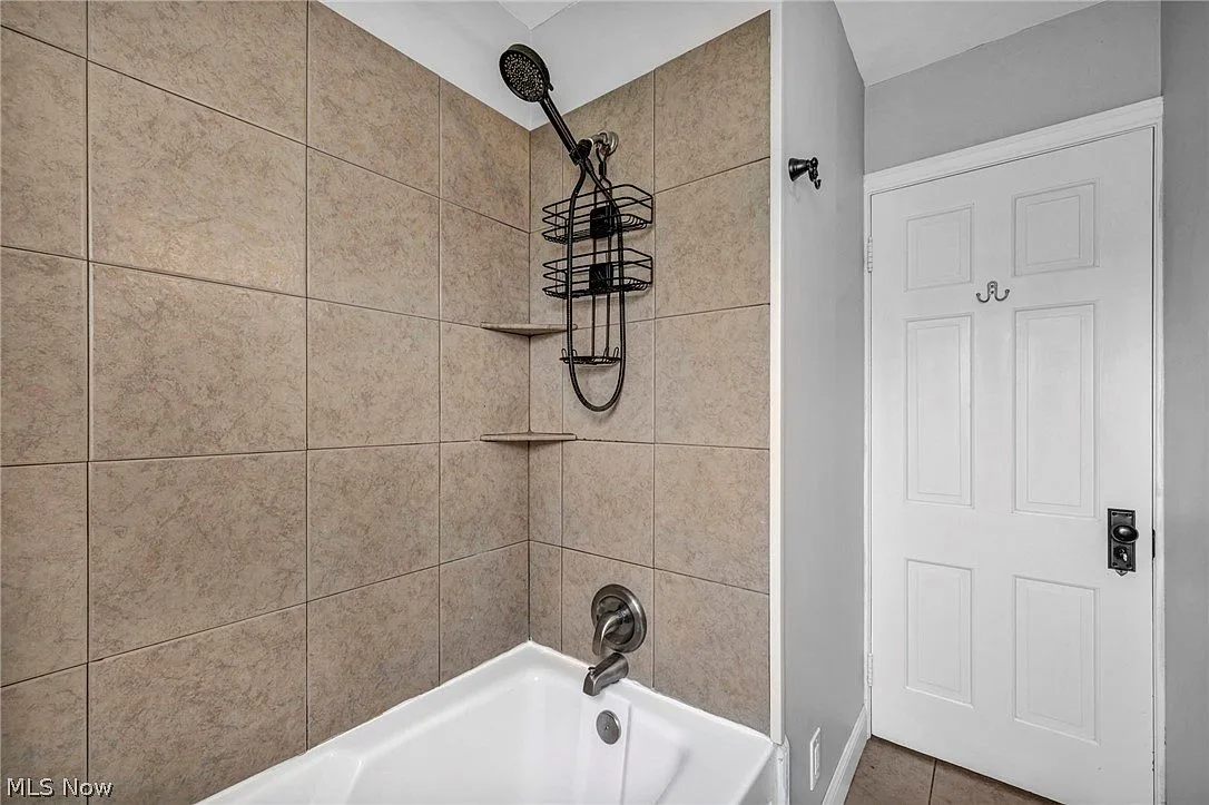 Bathroom shower with tan square wall tile and built-in shelves