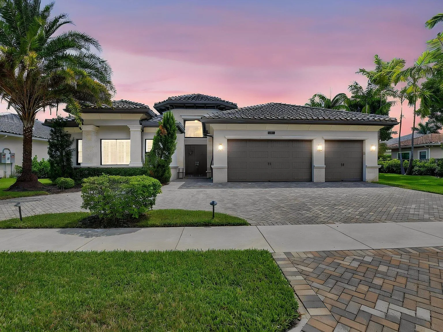 Front exterior of 16740 Strasbourg Lane at golden hour with a pink and purple sky over the Mediterranean-style roofline