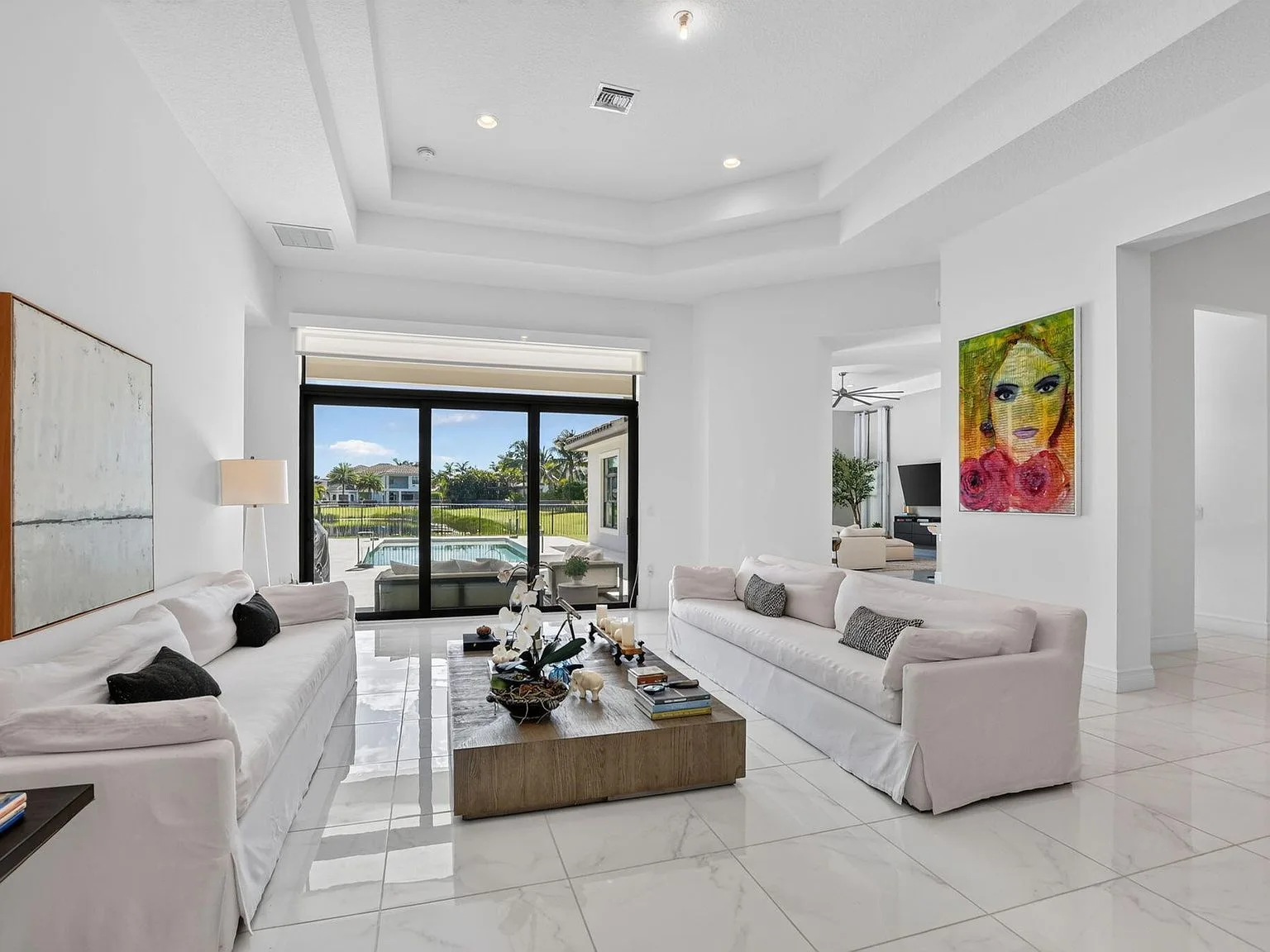 The open living room at 16740 Strasbourg Lane with a high tray ceiling and sliding glass doors