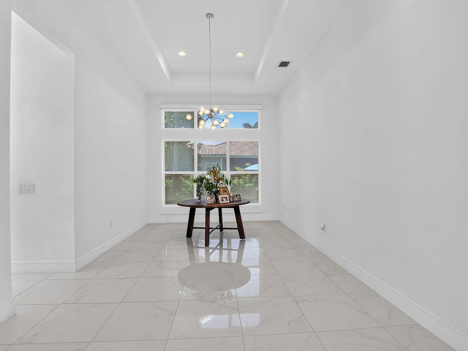 The dining room at 16740 Strasbourg Lane with a tray ceiling and natural daylight from the rear windows
