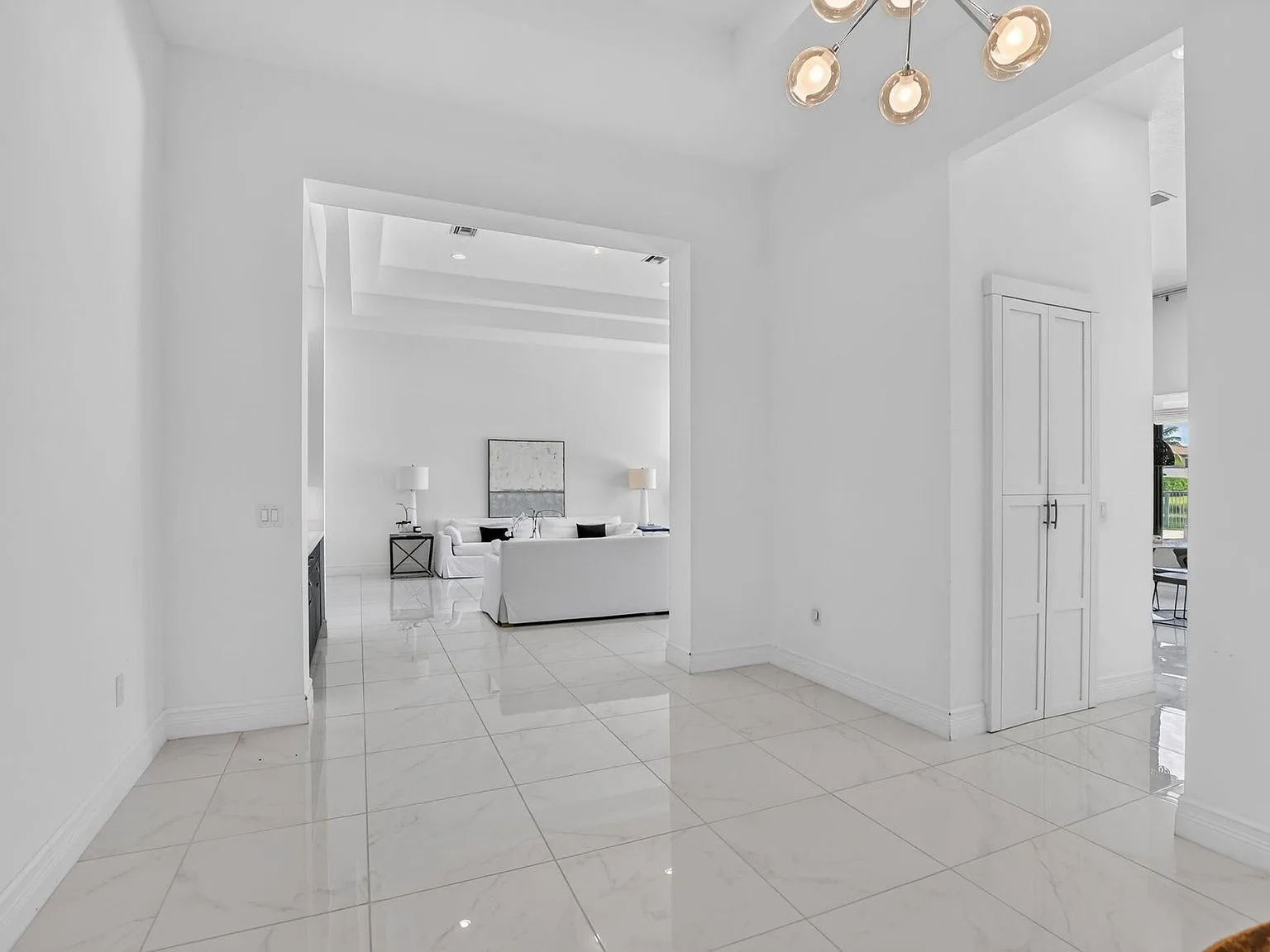 The foyer at 16740 Strasbourg Lane opening into the living room with volume ceilings and a chandelier