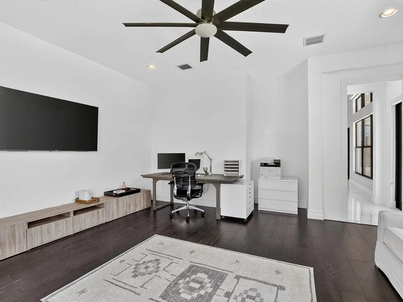 A flexible room at 16740 Strasbourg Lane set up as a home office with dark wood flooring