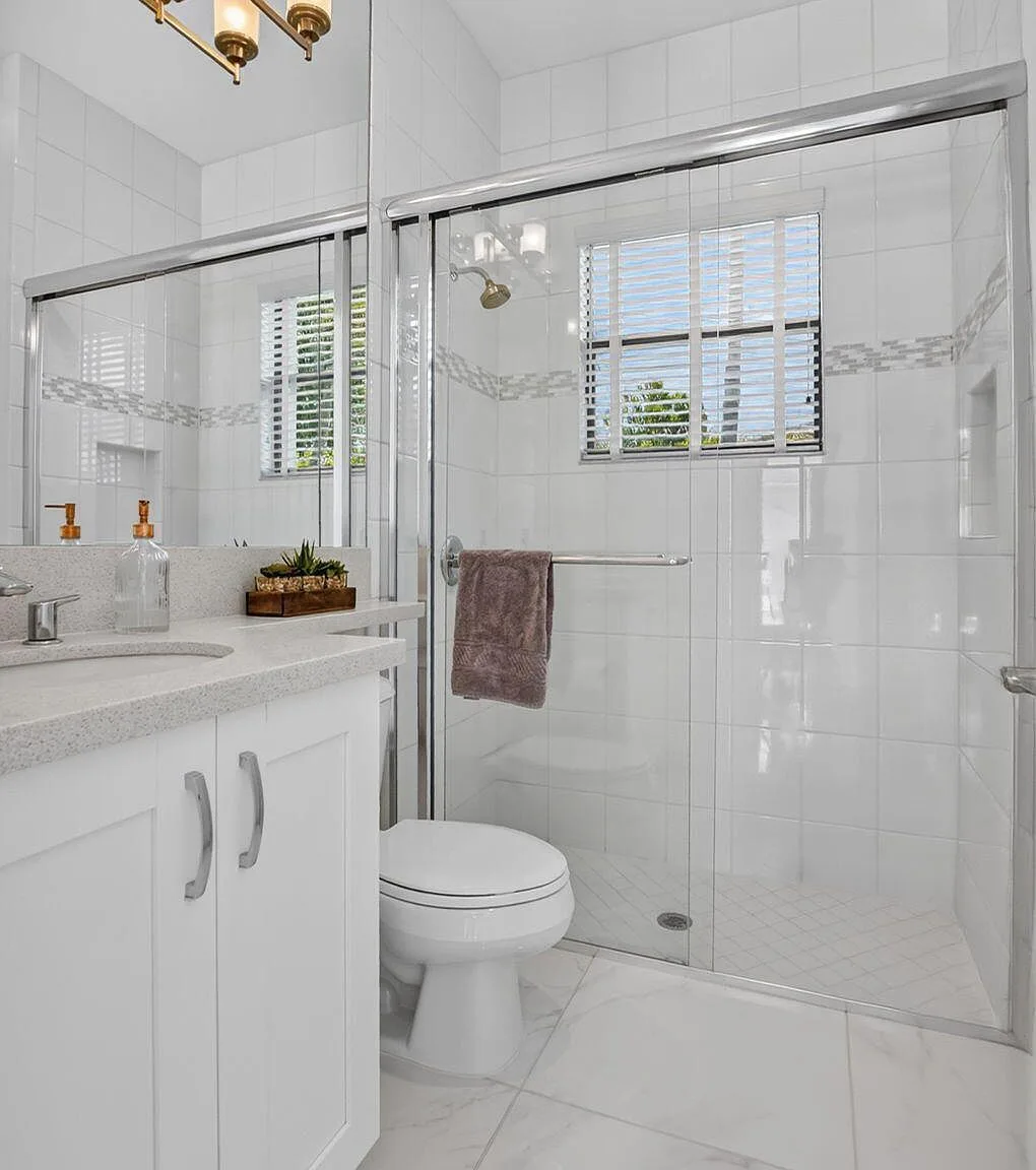 A guest bathroom at 16740 Strasbourg Lane with white tile walls, quartz counter and chrome fixtures