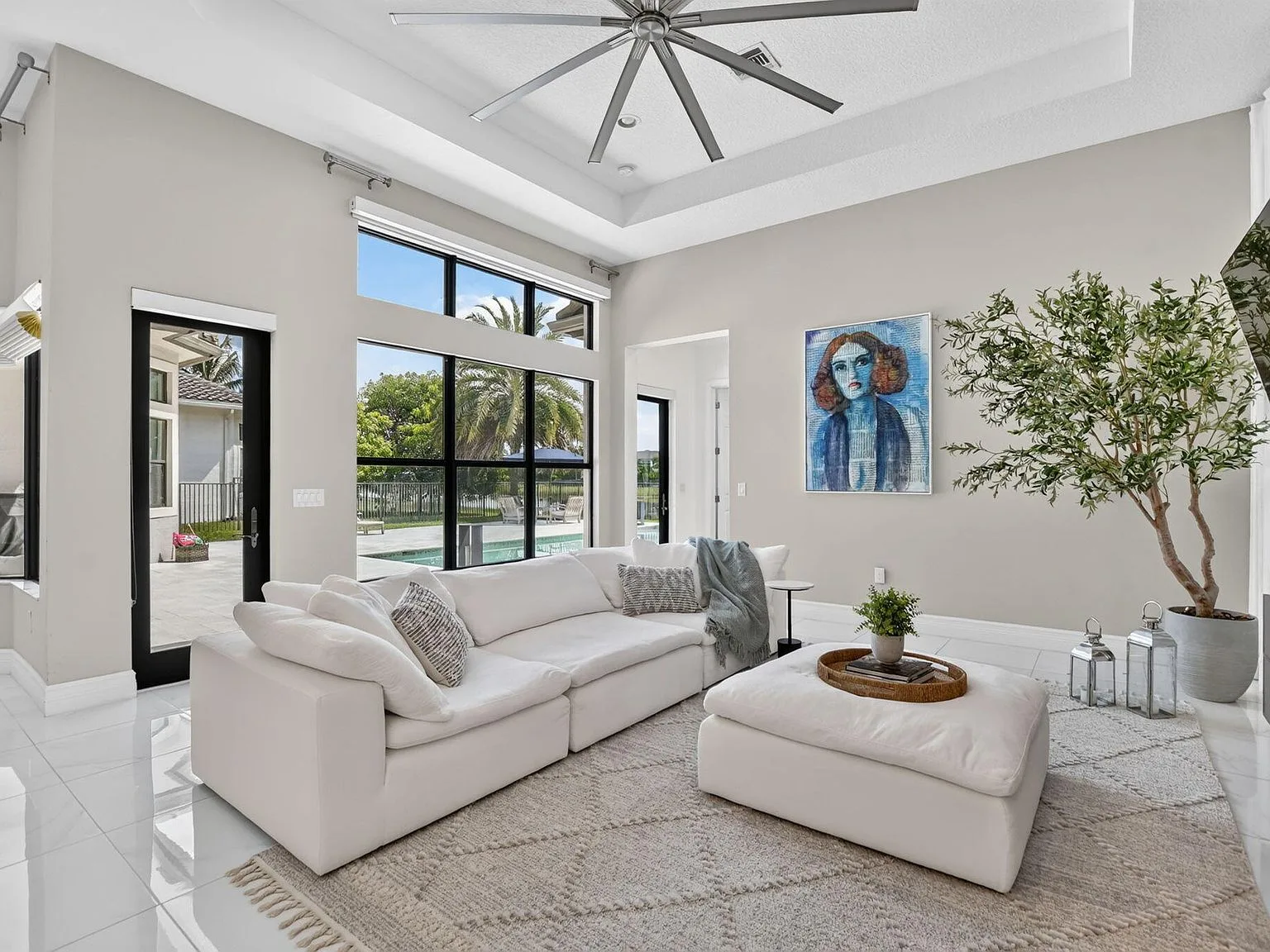 The great room at 16740 Strasbourg Lane with floor-to-ceiling windows overlooking the lake, tray ceilings and porcelain tile floors