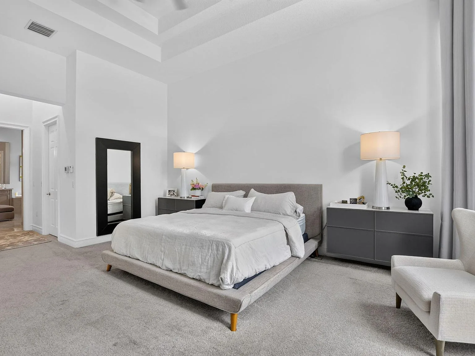 The primary bedroom suite at 16740 Strasbourg Lane with a high tray ceiling, neutral palette and soft daylight