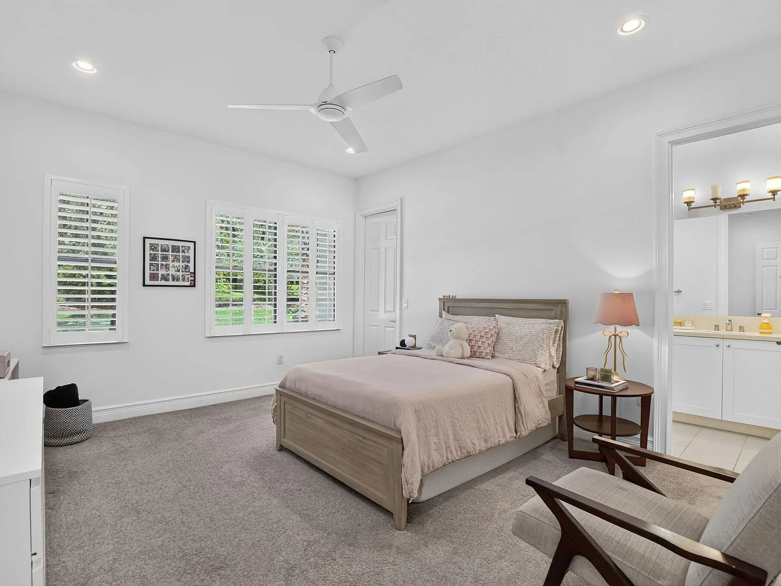 A guest bedroom suite at 16740 Strasbourg Lane with plantation shutters and a comfortable neutral finish