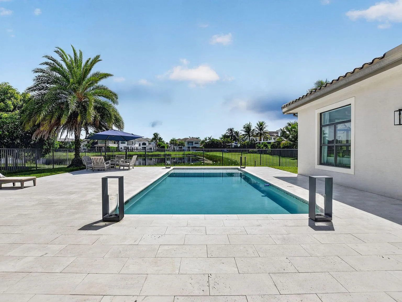 The private pool and paver patio at 16740 Strasbourg Lane overlooking the lake on a clear day in Delray Beach