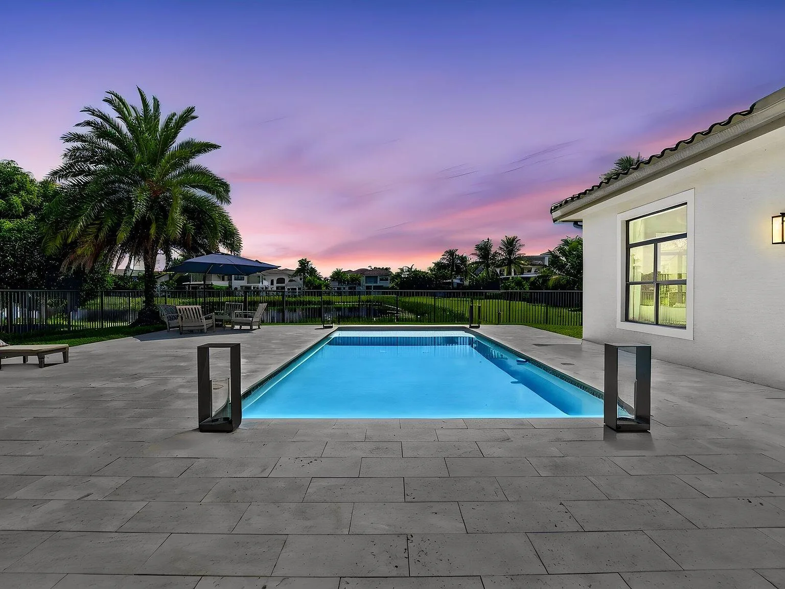 The backyard pool at 16740 Strasbourg Lane at twilight with a purple and orange sky