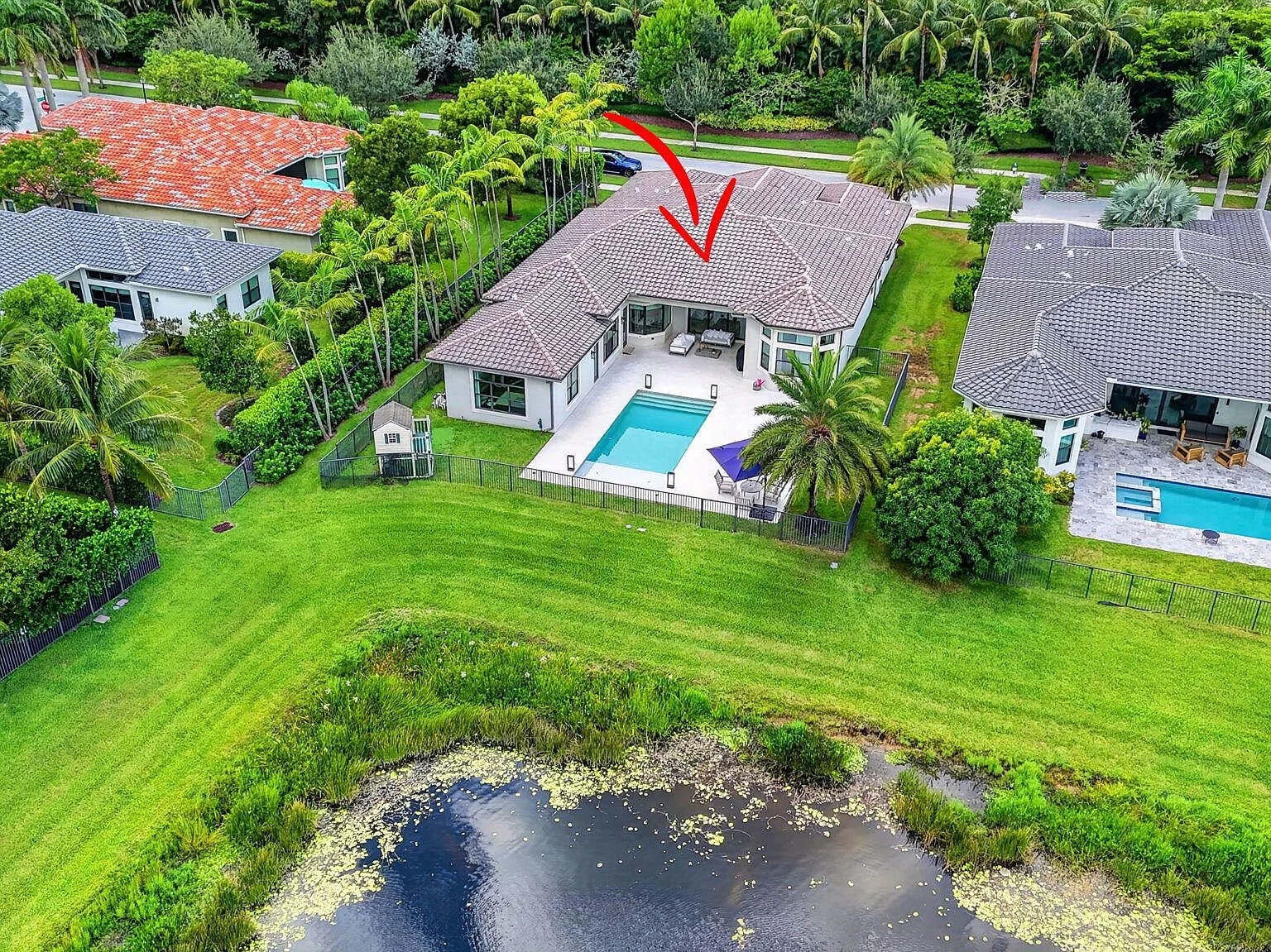 Aerial view of the lakefront lot and pool at 16740 Strasbourg Lane with the Seven Bridges neighborhood beyond