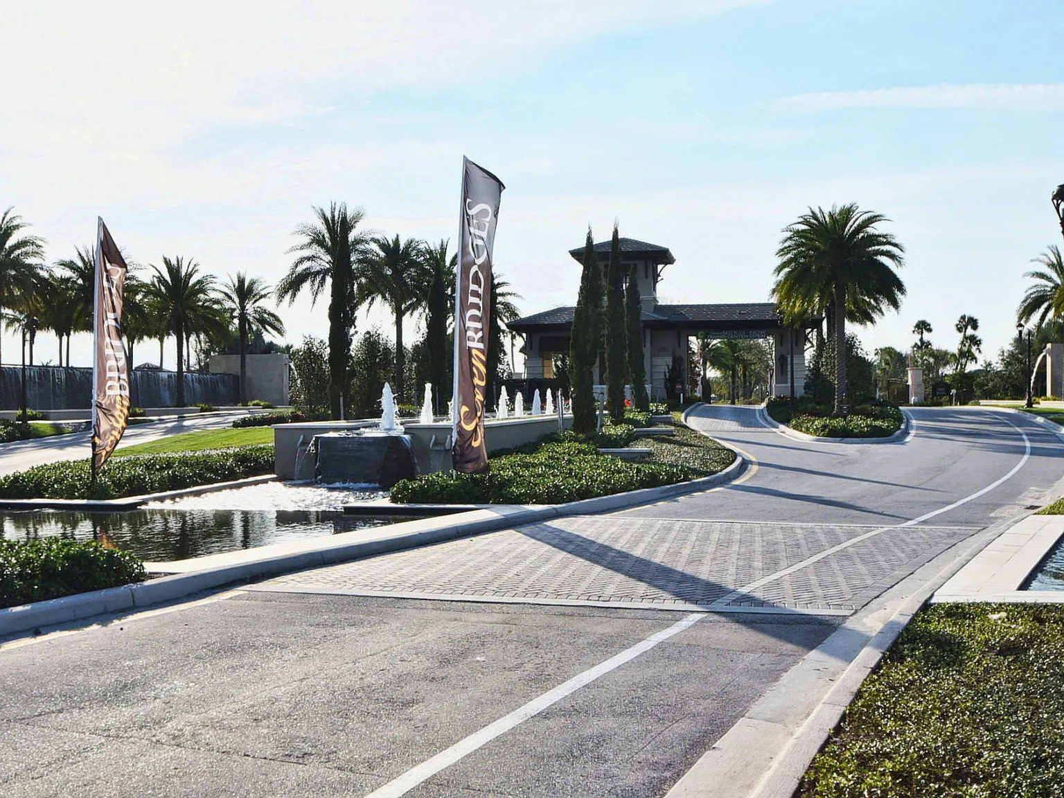 The Seven Bridges community gates with Mediterranean stonework, water features and a clear blue sky