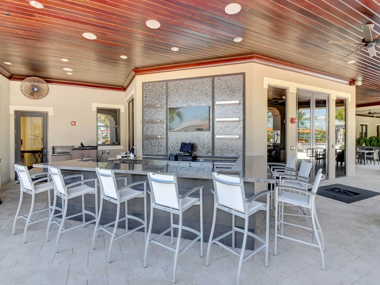 The outdoor kitchen and patio bar at 16740 Strasbourg Lane with a wood-slat ceiling and stone-look tile