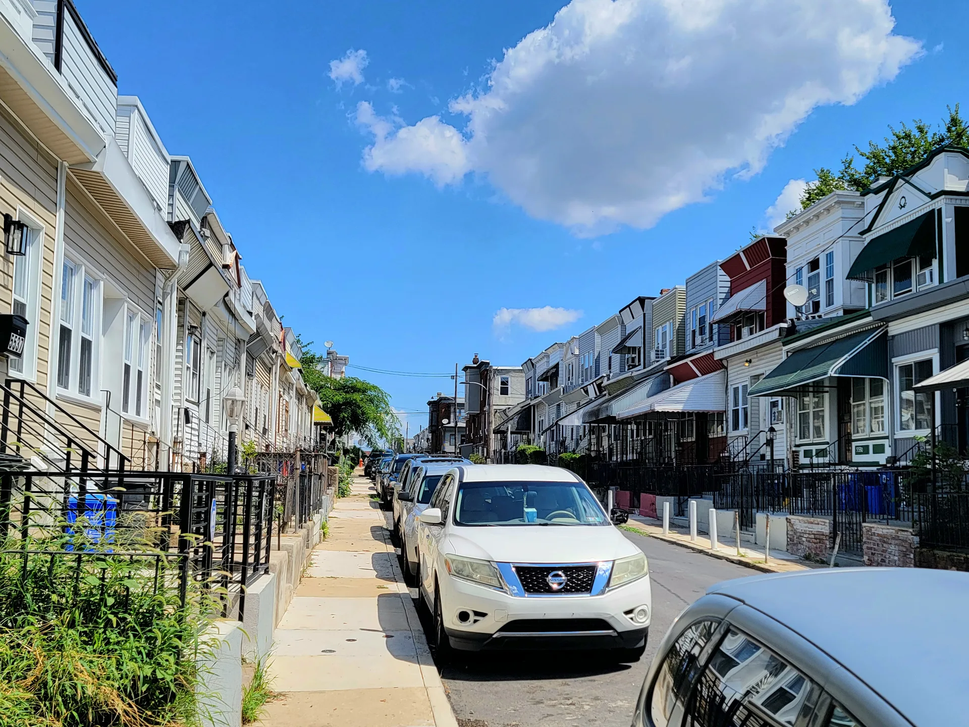 Street-level view of traditional row houses with porches and awnings in a Northeast Philadelphia neighborhood like Somerton