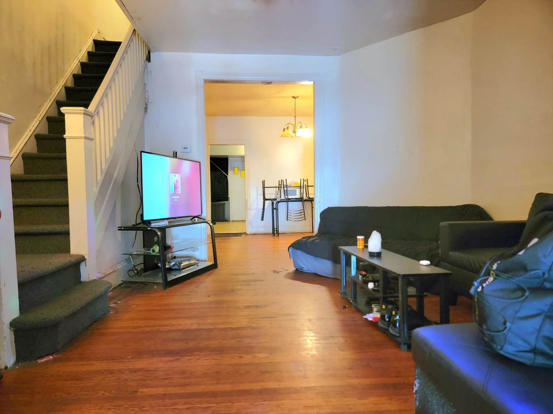The lived-in living room of a Philadelphia home with hardwood floors and an open staircase
