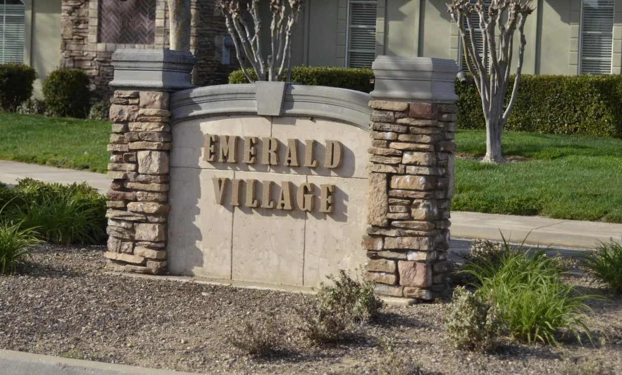 The Emerald Village community entrance sign with stone pillars and gold lettering in Galt, California.