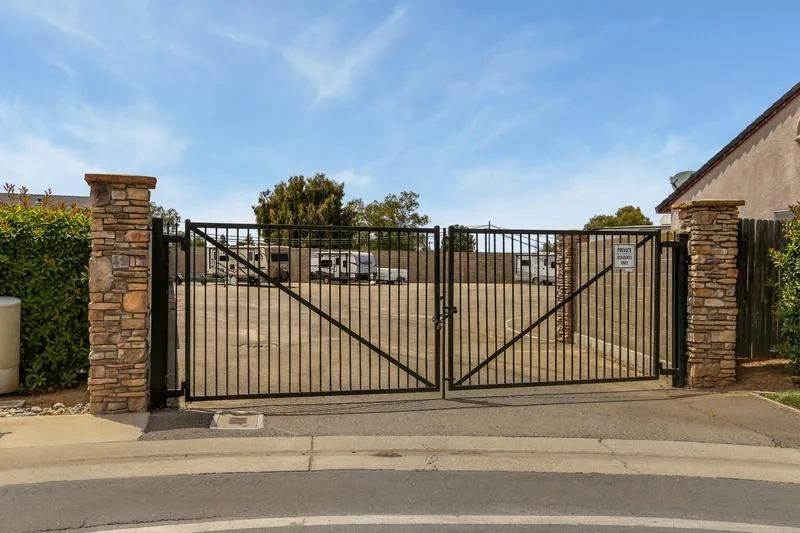 A gated entrance to a 55+ community with stone pillars and secured parking beyond.