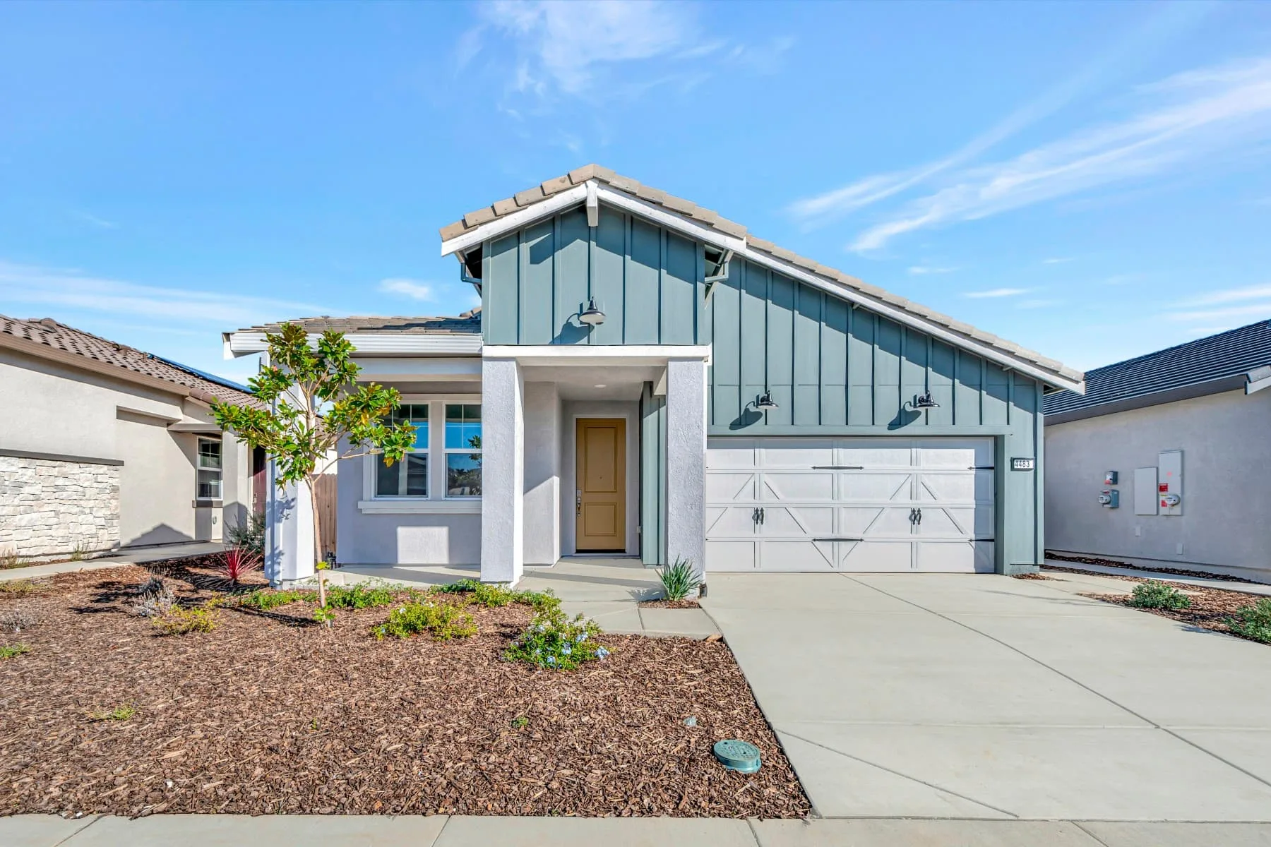 A modern new-construction home with blue-gray siding and a tile roof in a Northern California 55+ community