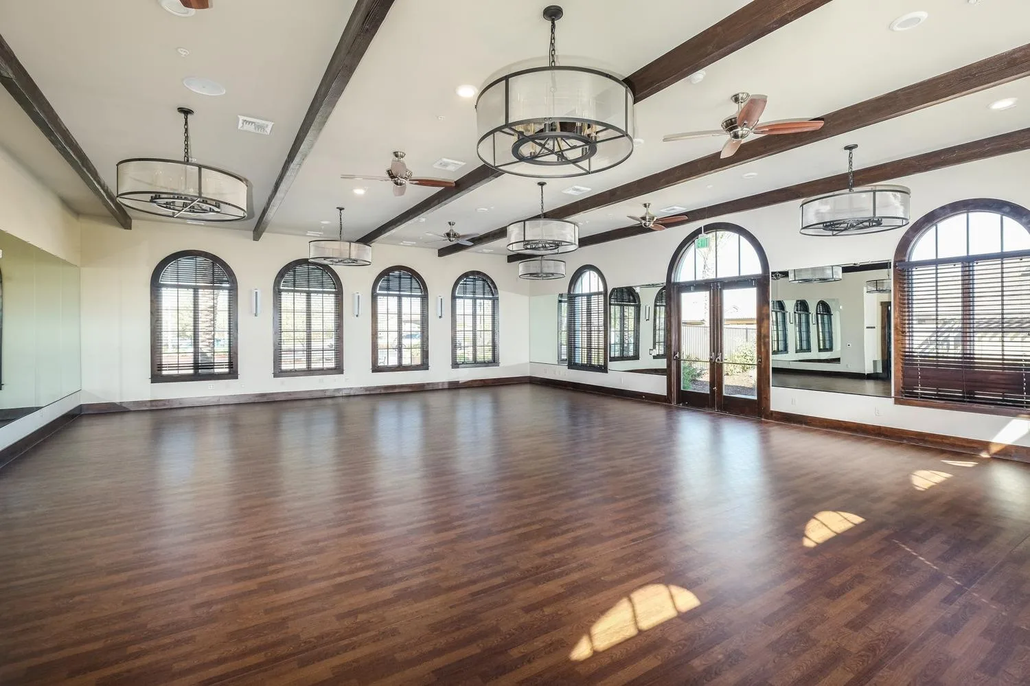 A bright, spacious community studio with wood beams and arched windows, ready for classes and gatherings in a Northern California 55+ community