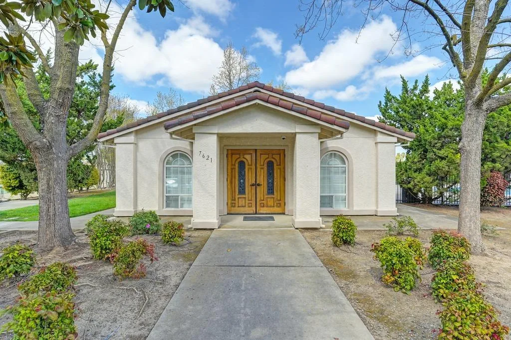 A clean Mediterranean-style stucco home exterior with a tile roof and manicured landscaping