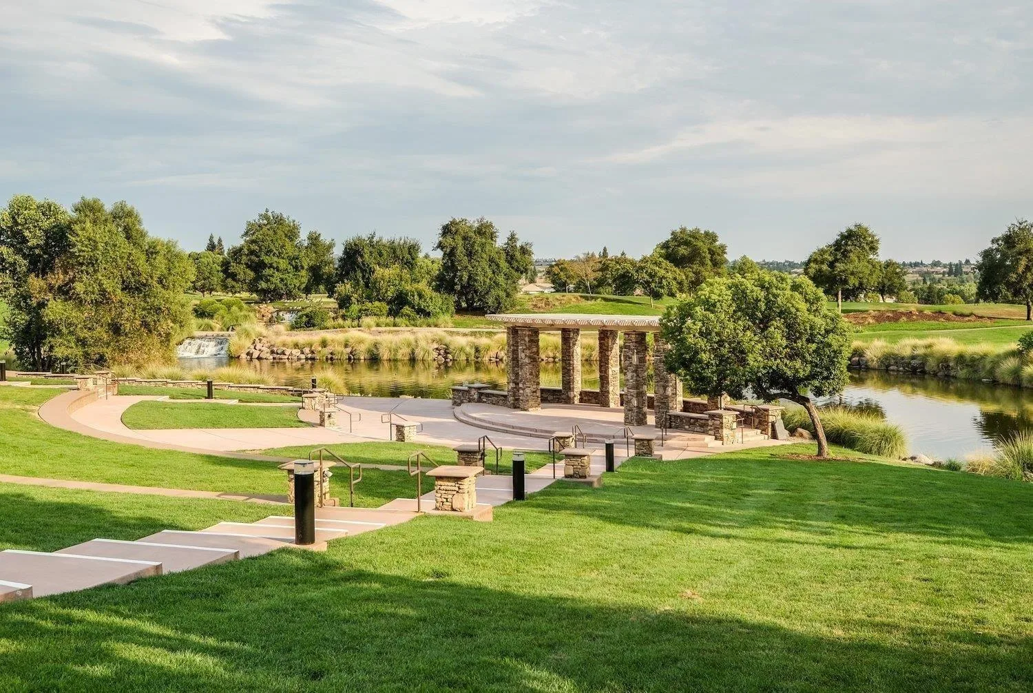 A stone pavilion beside a landscaped pond in a community park