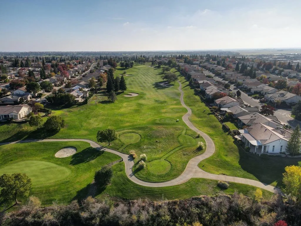 An aerial view of single-story homes along a golf course in a Northern California 55+ community