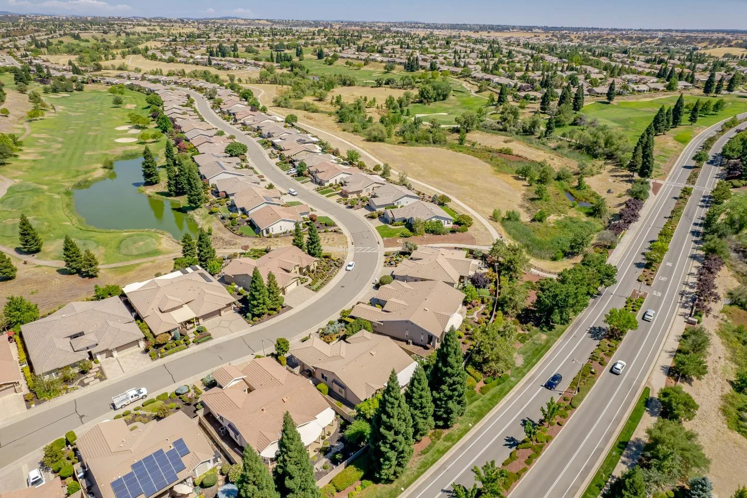 A drone view of single-story homes beside a golf course in a Northern California 55+ community