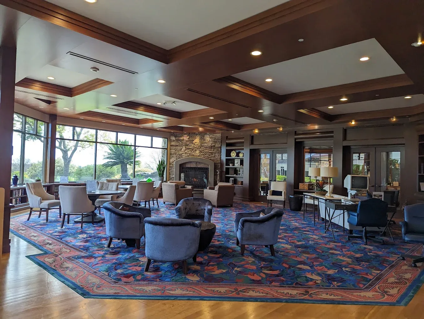 A spacious clubhouse lounge with wood-beamed ceilings and a stone fireplace in a Northern California 55+ community.
