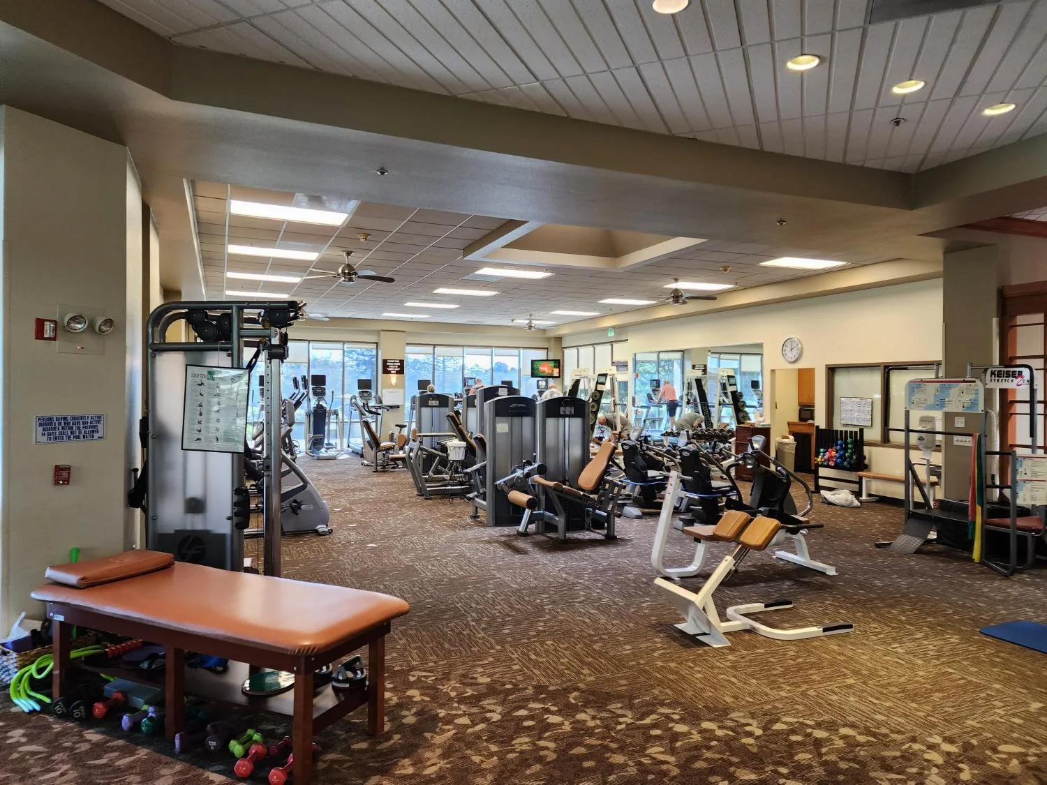 The fitness center at Sun City Roseville with exercise equipment and bright windows